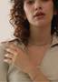 curly haired model wearing krizel classic oval shaped cubic zirconia gold plated tennis braceletand matching choker necklace